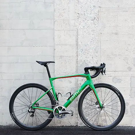 Grünes Rennrad vor weisser Wand